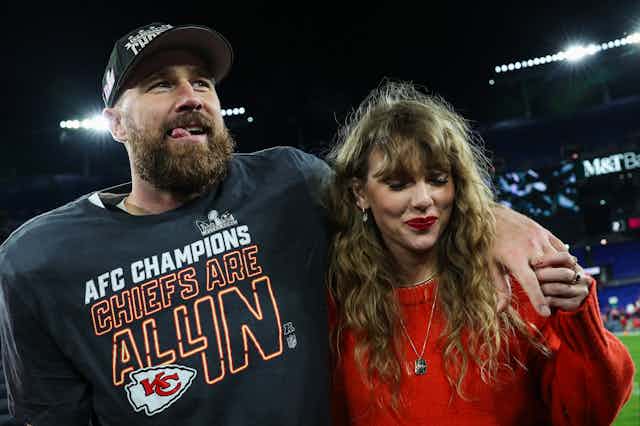 A man in a football championship T-shirt with his arm around a woman with curly brown hair.