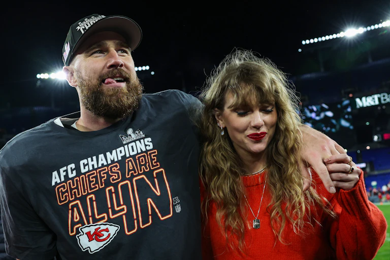 A man in a football championship T-shirt with his arm around a woman with curly brown hair.