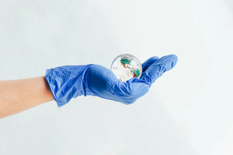 Hand wearing nitrile glove holding a glass globe