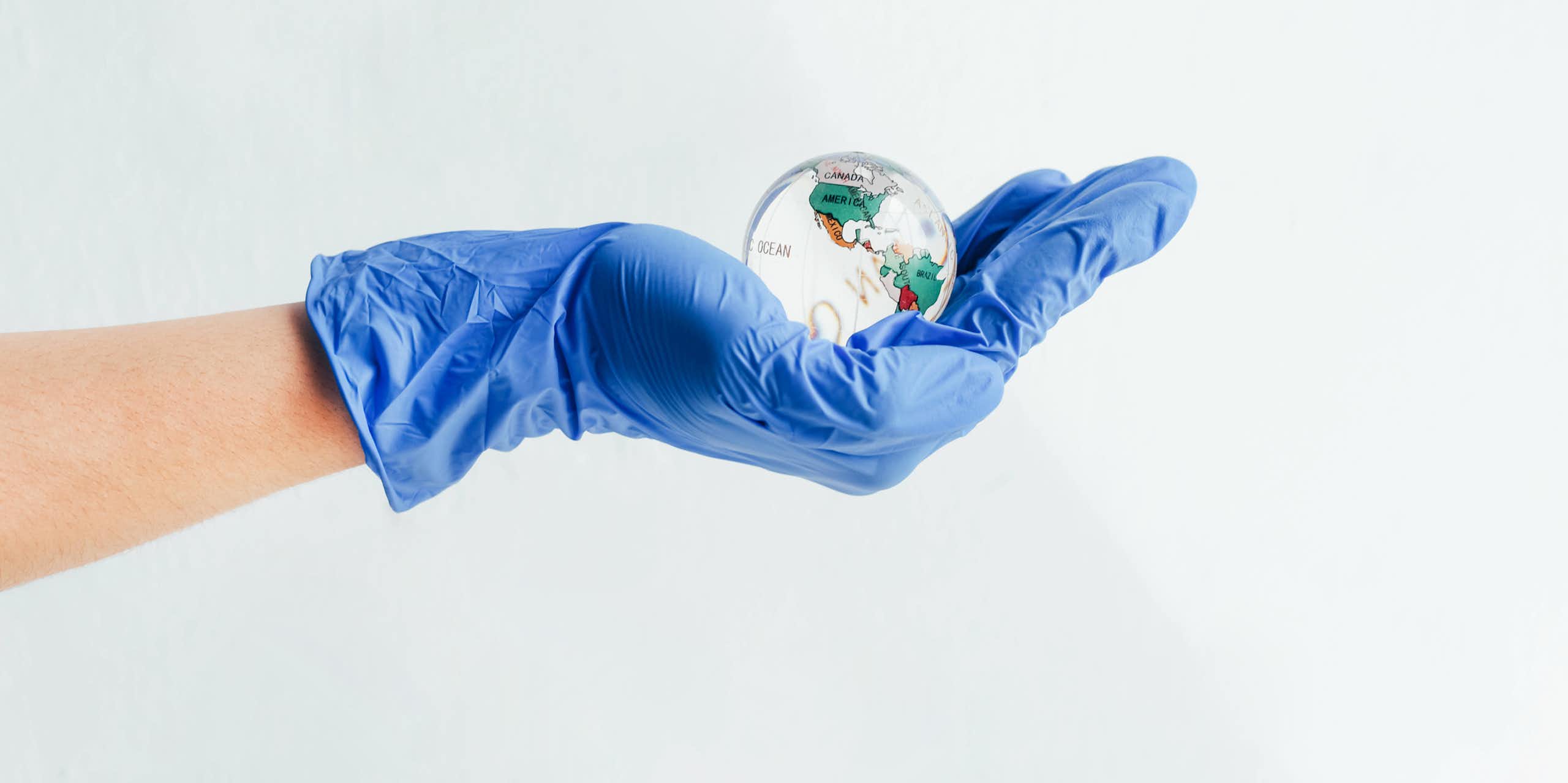 Hand wearing nitrile glove holding a glass globe 