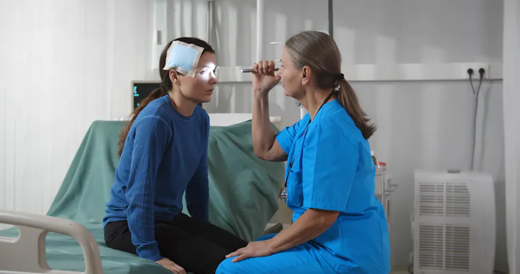 A girl with a bandage on her head is examined by a health-care professional.