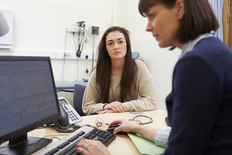 Female doctor looking at computer screen, female patient looking on