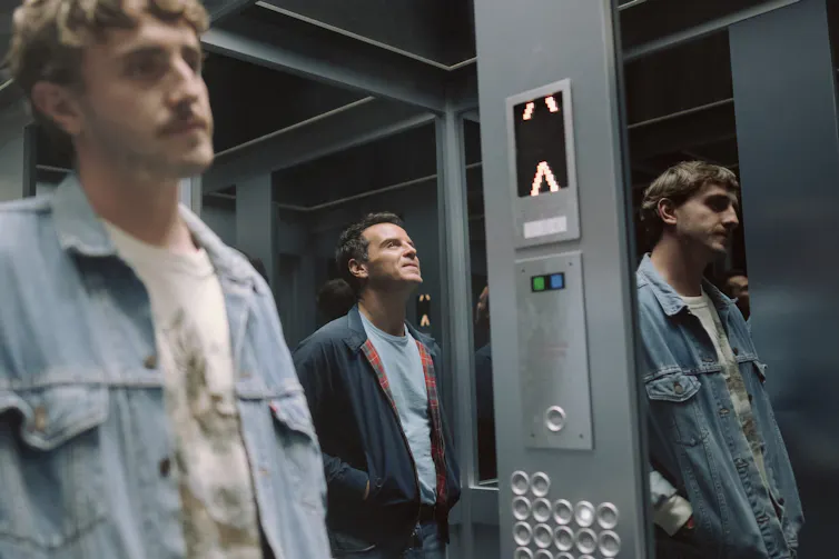 Harry and Adam stand in a lift.