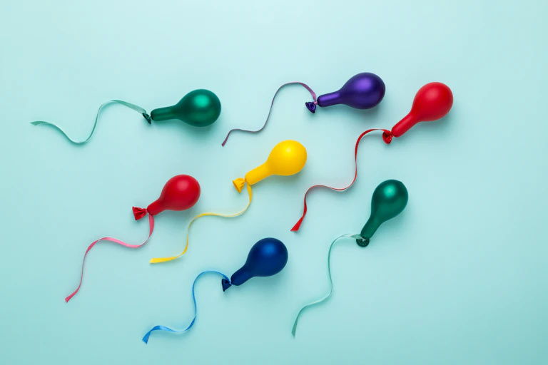 Colorful balloons in spermatozoid shape on blue.