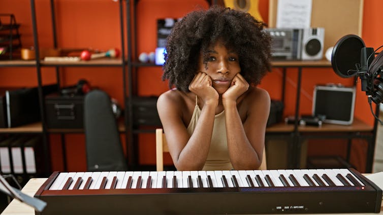 black woman sat at a keyboard, looking fed up.