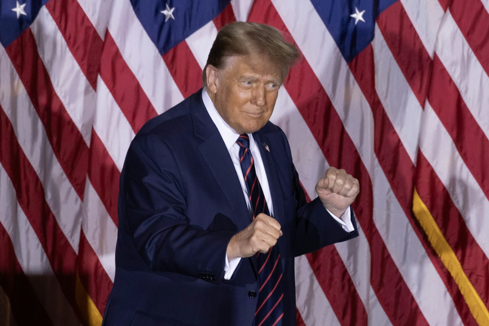 Donald Trump making fists in front of an American flag.
