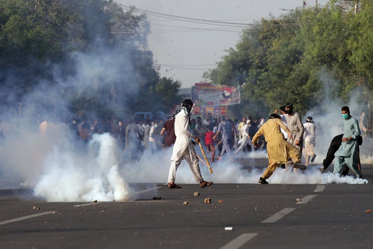 Protestors on a road kicking away tear gas shells fired by police.