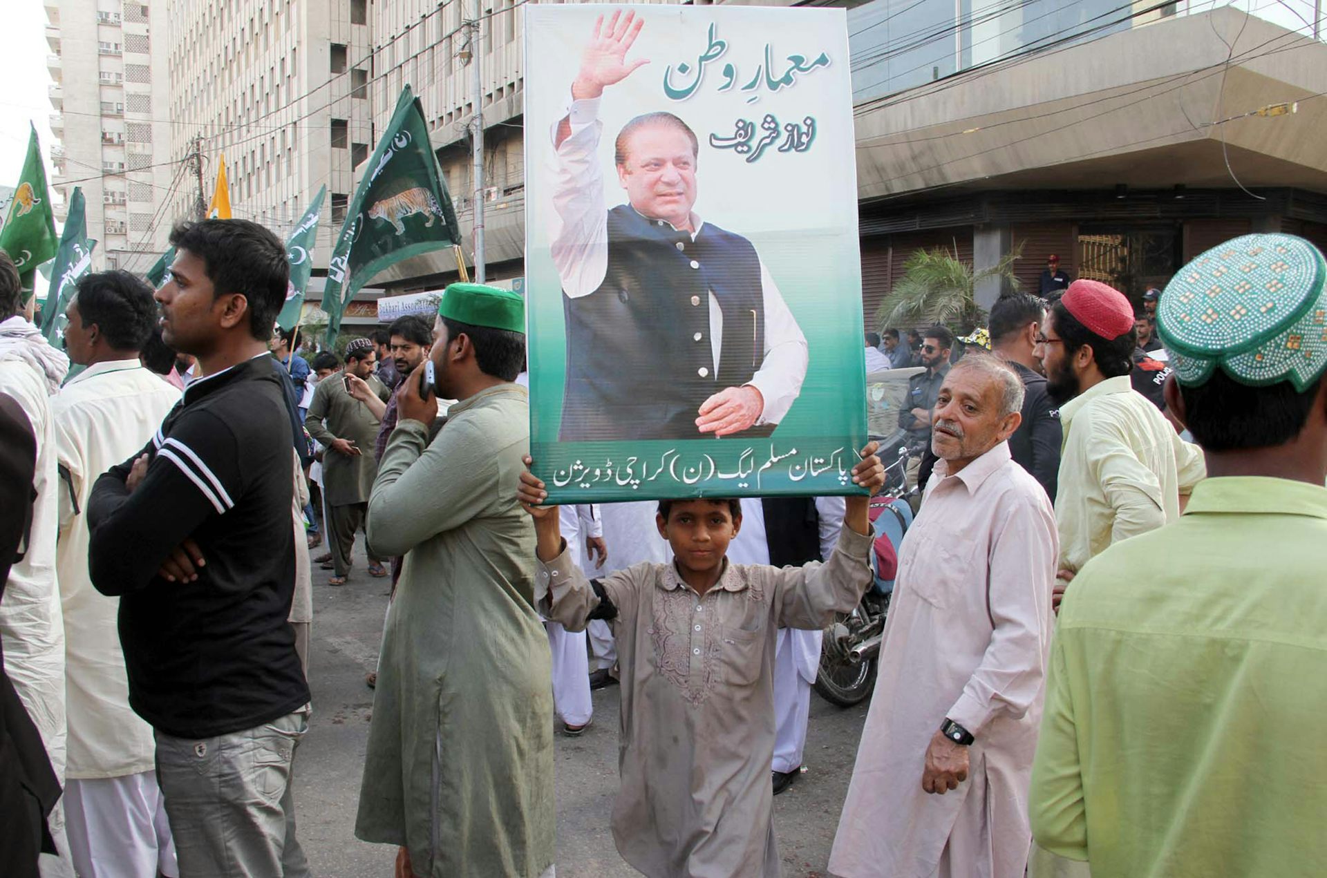 A child at a demonstration holding aloft a picture of Nawaz Sharif.