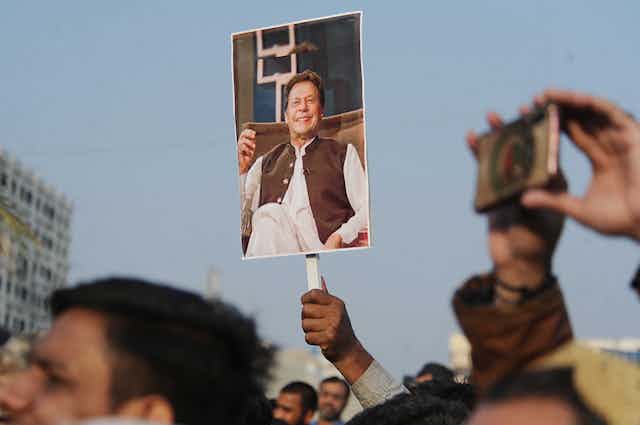People at a political rally holding a picture of Imran Khan in the air.