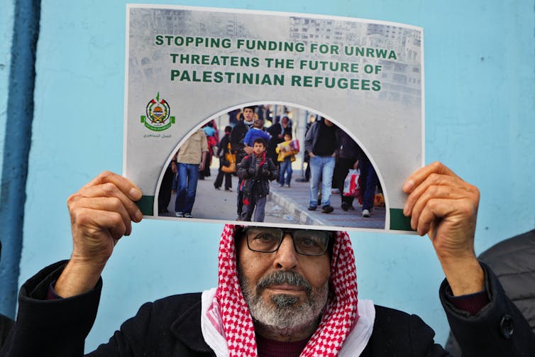 A man holds a placard reading: stopping funding for UNRWA threatens the future of Palestinian refugees.
