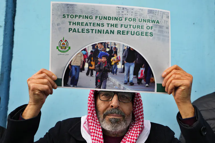 A man holds a placard reading: stopping funding for UNRWA threatens the future of Palestinian refugees.