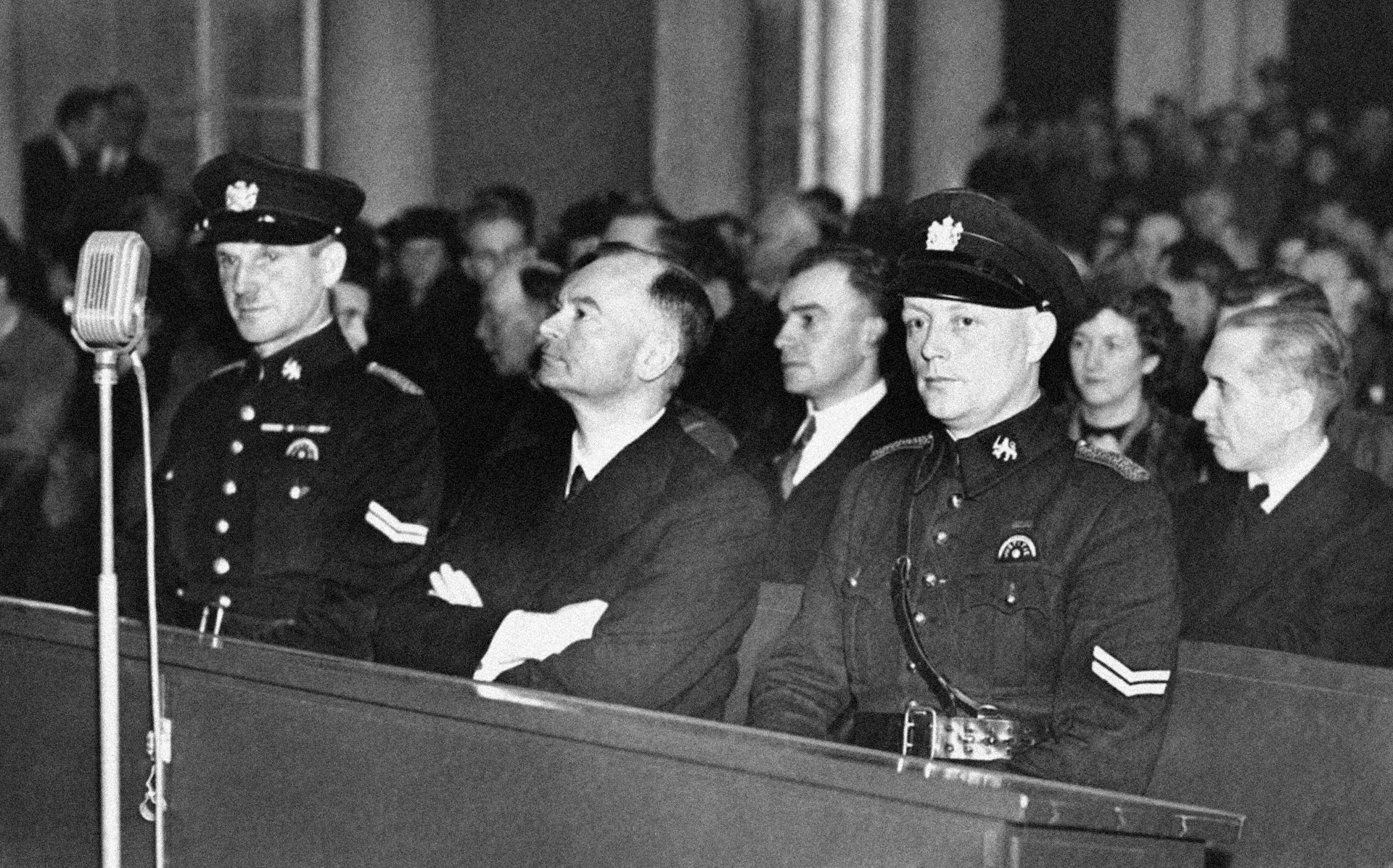 A man sits on a bench flanked by two men in uniform