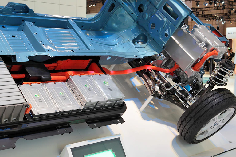 A car chassis with part of the floor removed, revealing rows of silver boxes
