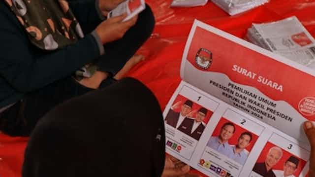A woman folds ballot papers for Indonesia's presidential election 2024
