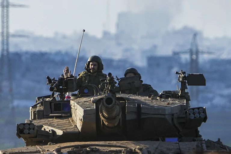 Two soldiers in a tank, one with his hand raised.