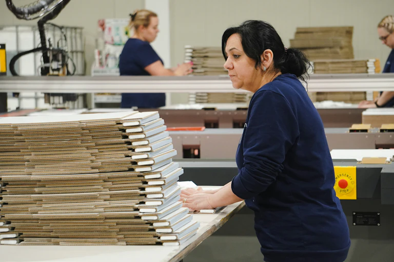 Factory worker folds a cardboard box