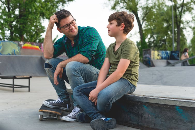 A man talks to a boy at a skate park.