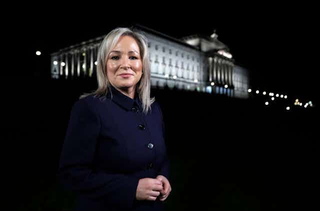 Michelle O'Neill standing in front of Stormont at night. 