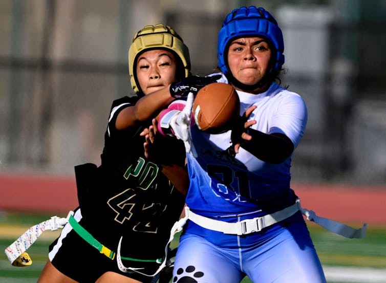 Two teenaged girls fight for a ball.