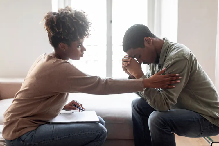 A black woman consols a young black man.