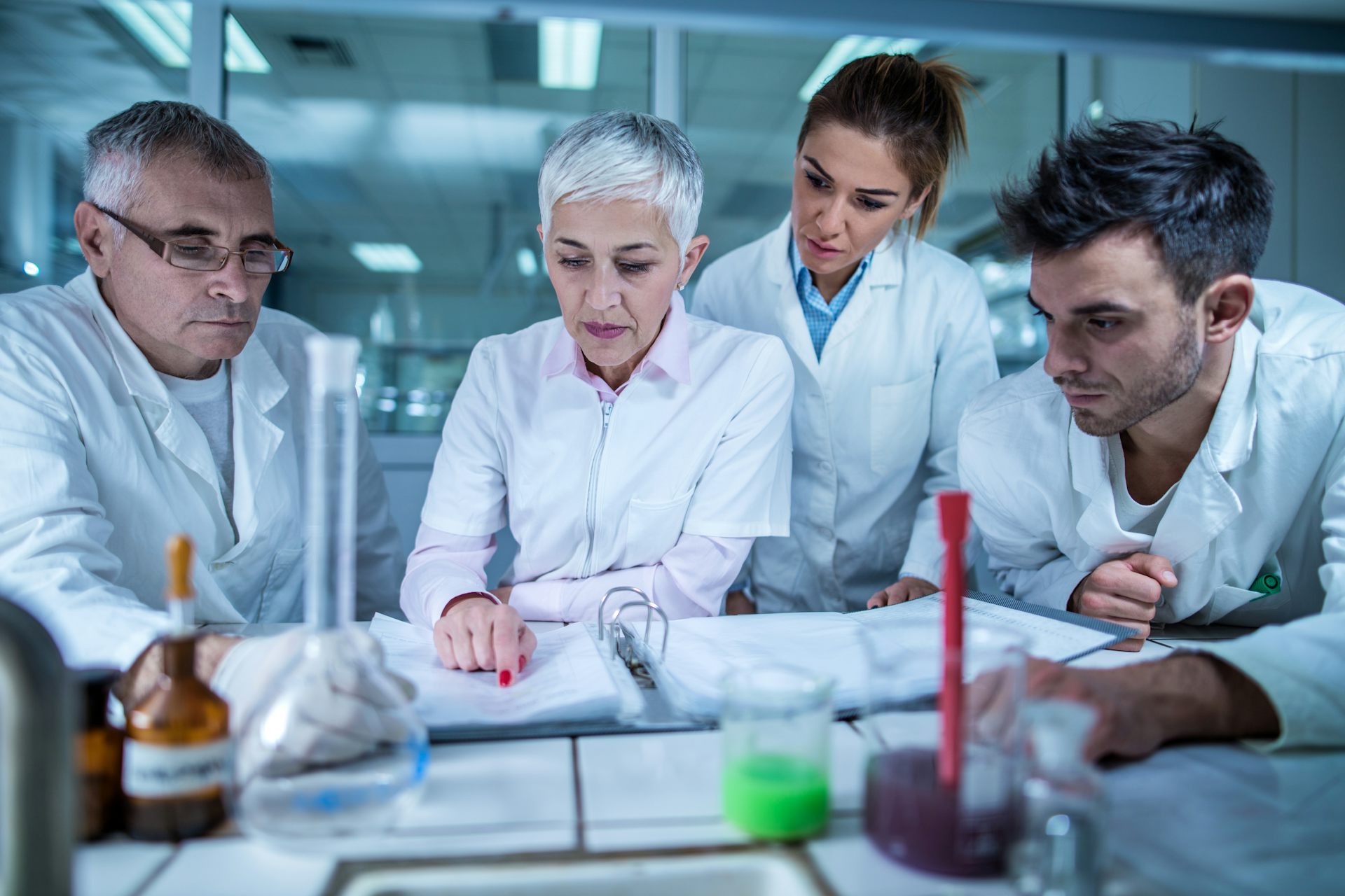 Four researchers look at an open notebook.