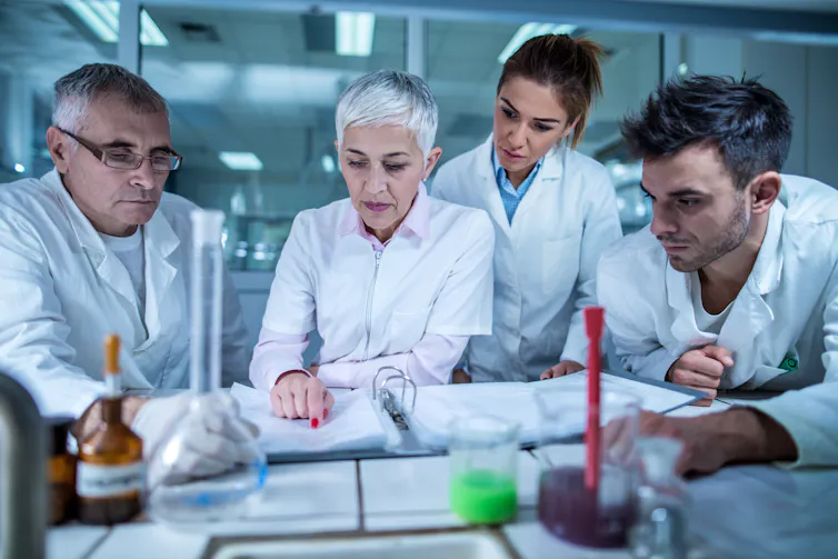 Four researchers look at an open notebook.