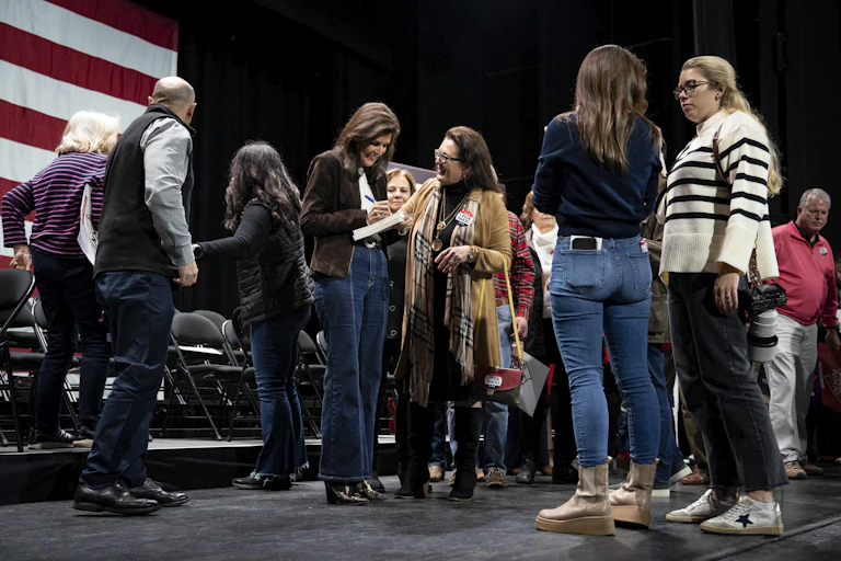 A group of people on a stage with a brown-haired woman signing something.