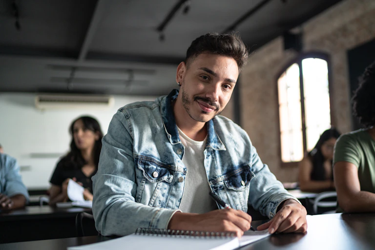 A male adult student in the classroom with female students in the background.