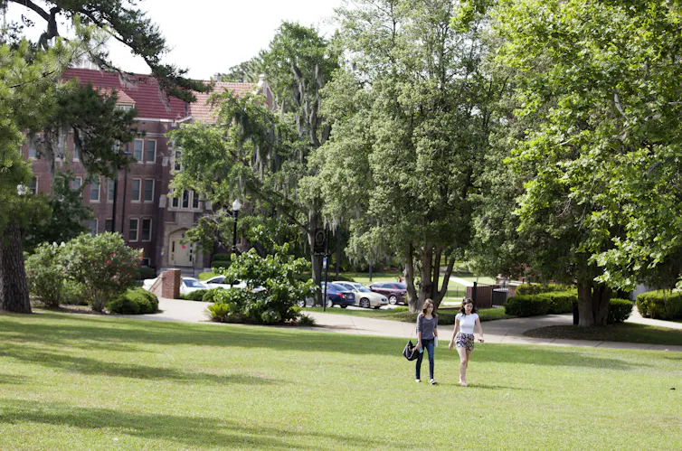Two students walk across an open space on a college campus.