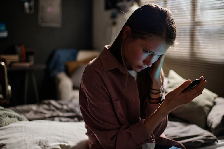 An upset woman looks at her phone