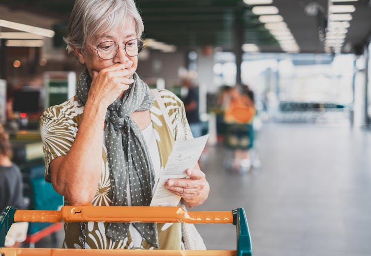 A woman looks at her supermarket receipt.