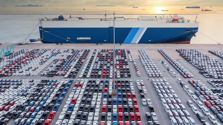 Thousands of new cars parked on a wharf waiting to be loaded onto a cargo ship