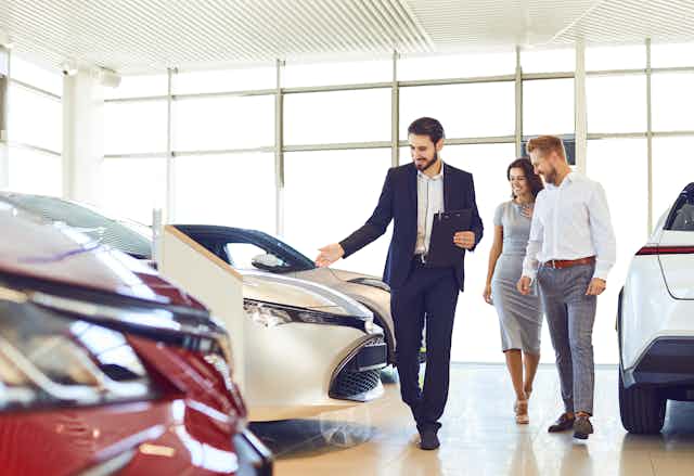 Car salesman showing a man and a woman cars in a showroom