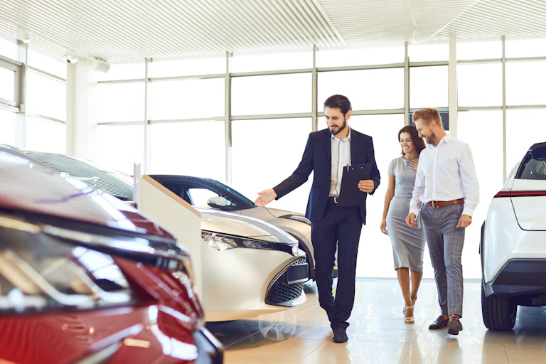 Car salesman showing a man and a woman cars in a showroom