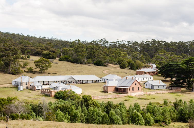 Photo of Darlington, a convict site on Maria Island, Tasmania, take from some distance away to show all of the buildings together, with trees in the foreground and background