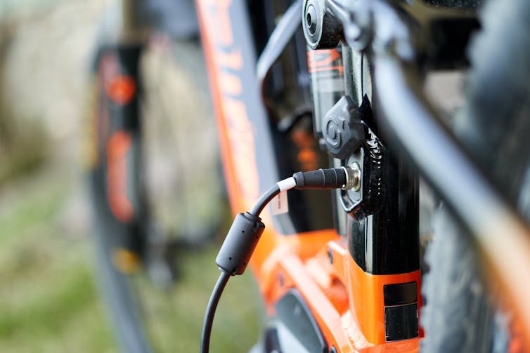 Close-up of orange and black e-bike with charger plugged in