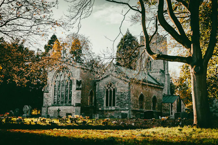A rural church and a graveyard with trees.