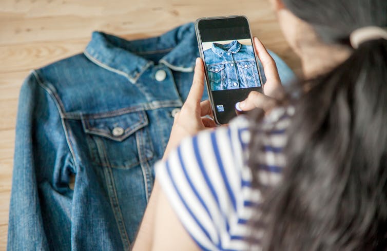 Woman using phone to take photo of a shirt.