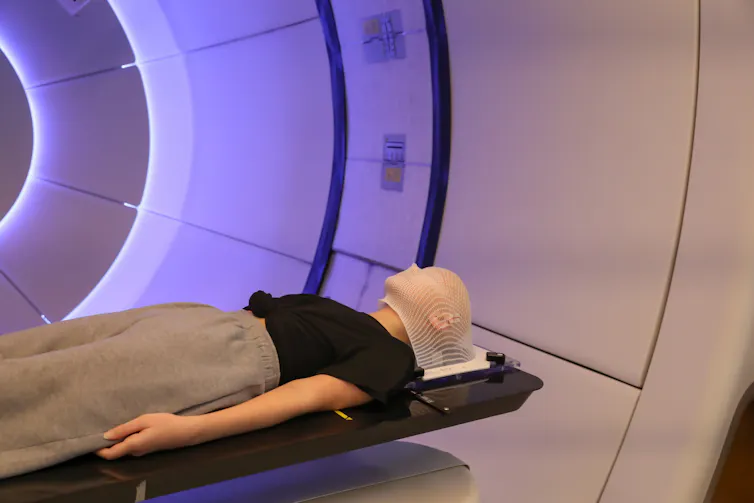 A person with lying on a table with a net-like structure over their head
