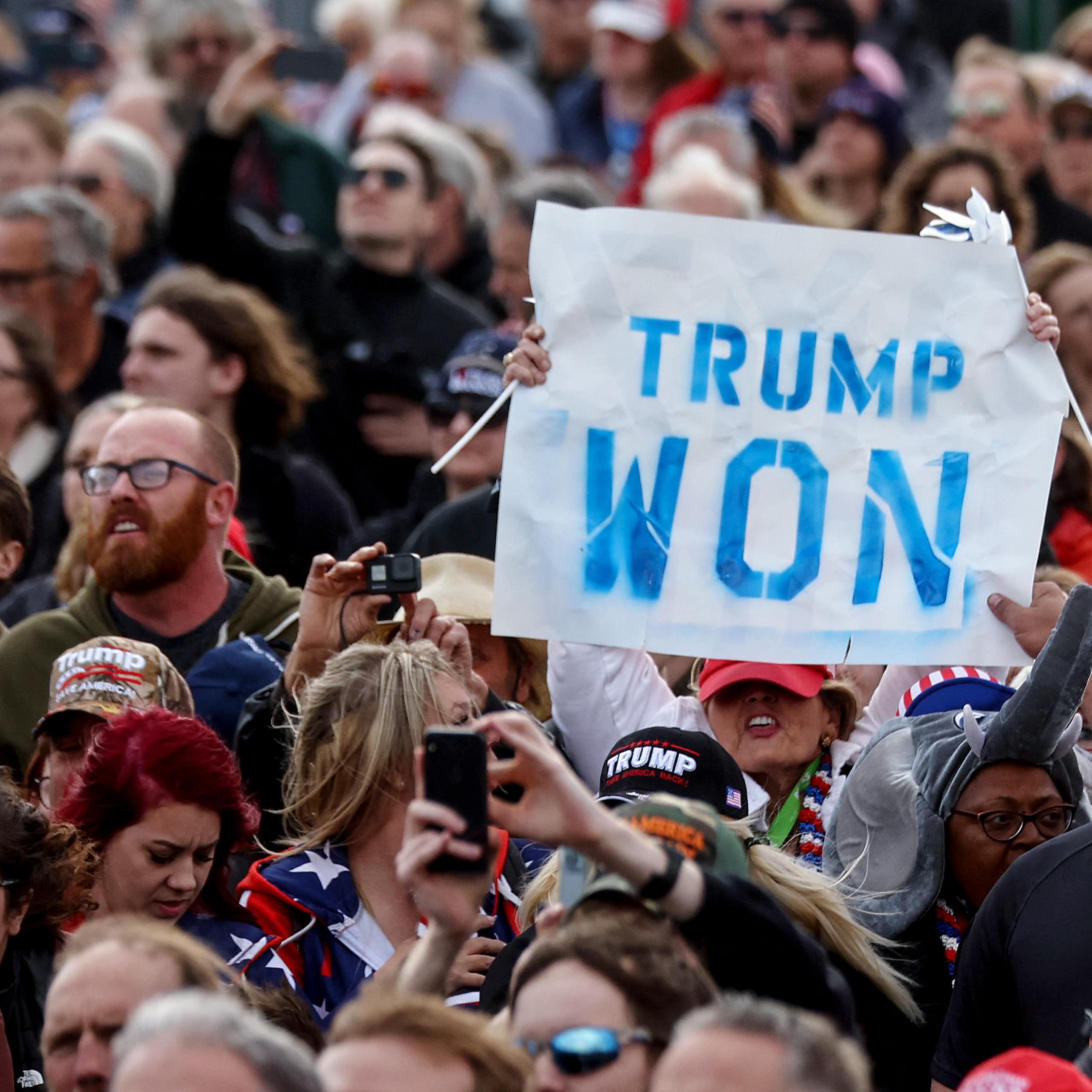 Une personne brandit une pancarte « Trump won » au milieu d'une foule