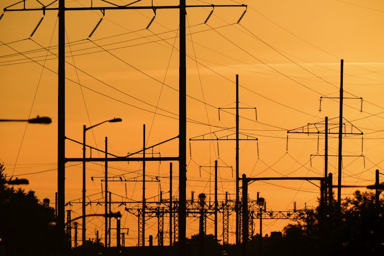 Electrical towers and power lines shown against a sunset.