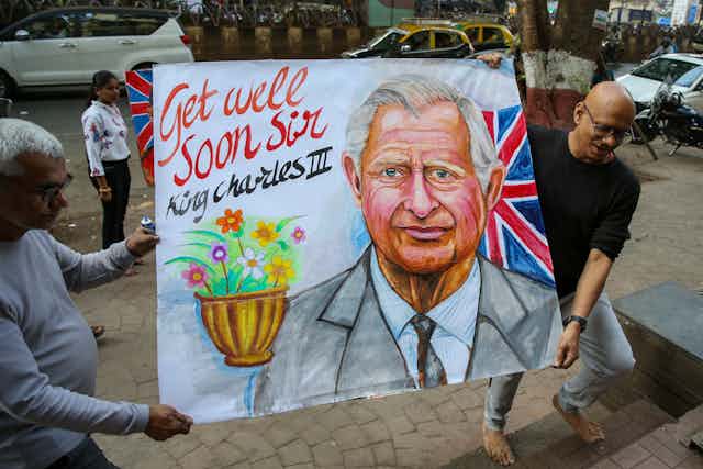 Two men carrying 'get well soon' banner for King Charles