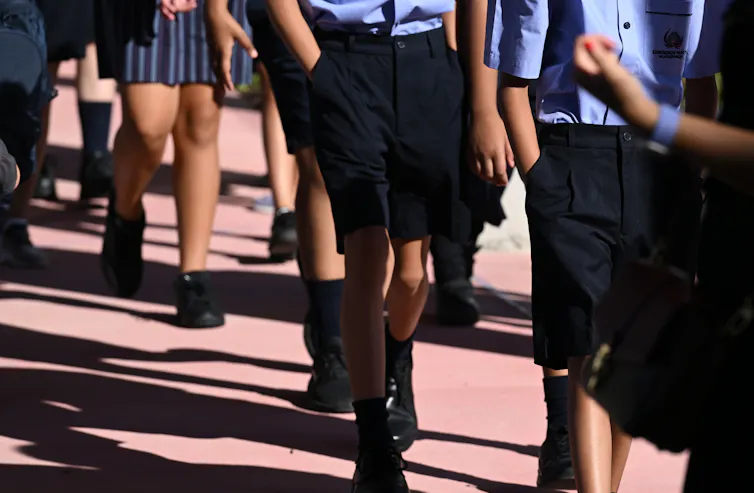 A group of students in uniform walking outside.