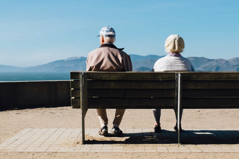Older woman and man sit on a bench seat