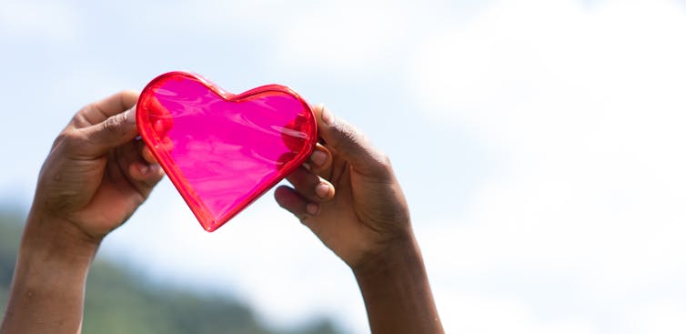 Brown hands holding a heart.