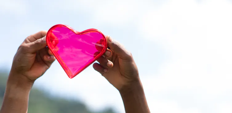 Brown hands holding a heart.