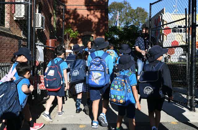 Students walk through the gates of a school.