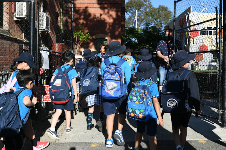 Students walk through the gates of a school.