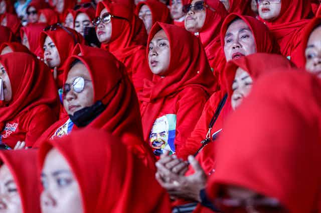 A group of Indonesian women wearing red headscarves in a crowd
