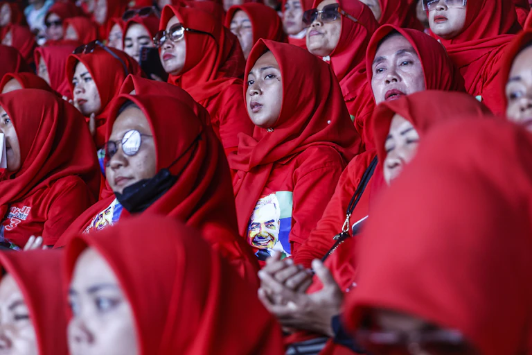 A group of Indonesian women wearing red headscarves in a crowd
